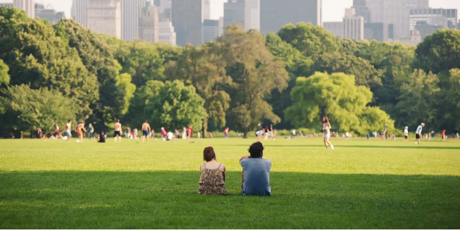 People relaxing in a park with a city skyline in the background